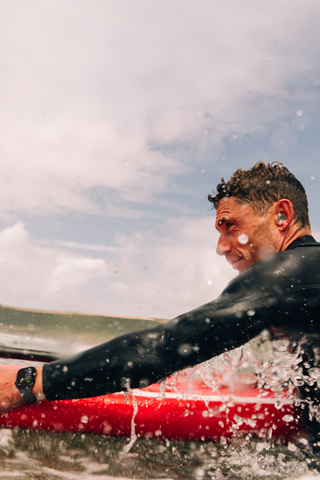 Een man met een supboard in het water, met om zijn pols een Apple Watch Series 10.